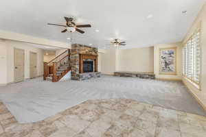 Unfurnished living room with ceiling fan, a stone fireplace, baseboards, carpet flooring, and recessed lighting