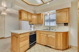 Kitchen featuring a peninsula, light brown cabinets, baseboards, light countertops, and a sink