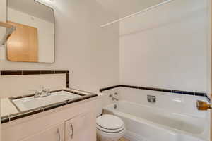 Bathroom with vanity, a bathtub, toilet, and tasteful backsplash