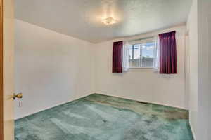 Primary Bedroom  with a textured ceiling, visible  and carpet