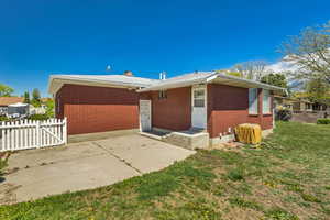 Back of property with fence, a patio, a lawn, and brick siding