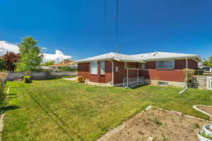 Back of property featuring a fenced backyard, a lawn, and brick siding