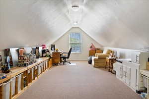 Carpeted home office with vaulted ceiling and baseboards