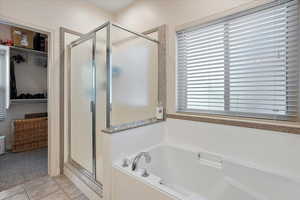 Full bathroom with tile patterned floors, a spacious closet, a stall shower, and a garden tub