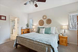Carpeted bedroom featuring baseboards, ceiling fan, and connected bathroom