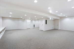Finished below grade area featuring light colored carpet and recessed lighting