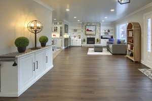 Living area with dark wood-style flooring, recessed lighting, ornamental molding, and a fireplace