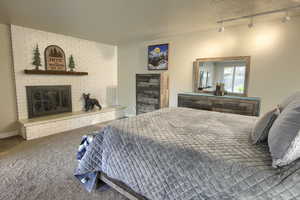 Bedroom/Family room with a fireplace, track lighting, carpet, and a textured ceiling