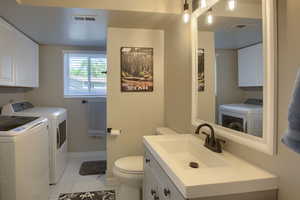 Bathroom/Laundry room with tile patterned floors, toilet, and washing machine and clothes dryer