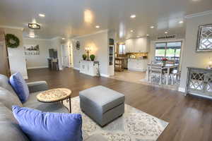 Living area with crown molding, recessed lighting, baseboards, and wood finished floors