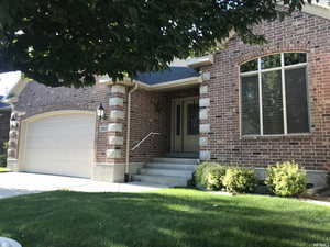 View of front of property with a garage, a front yard, driveway