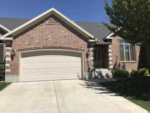 View of front of property featuring brick siding, a garage, and concrete driveway
