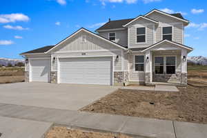 Craftsman-style home featuring an attached garage, board and batten siding, a mountain view, and stone siding