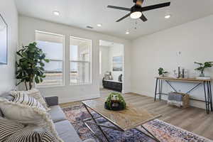 Living room with light wood-style floors, a ceiling fan, baseboards, and recessed lighting