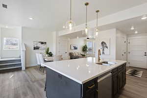 Kitchen with a sink, light countertops, light wood finished floors, and open floor plan