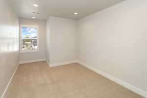 Spare room featuring visible vents, light carpet, baseboards, recessed lighting, and a textured ceiling