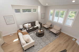 Living area featuring visible vents, lofted ceiling, wood finished floors, baseboards, and recessed lighting