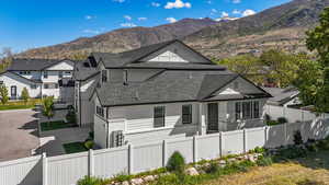 Exterior space featuring driveway, a mountain view, fence private yard, and roof with shingles