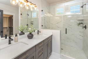 Bathroom featuring double vanity, a marble finish shower, and a sink