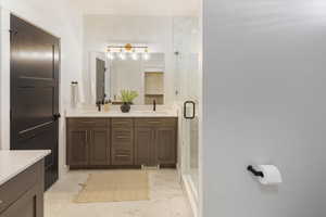 Bathroom with a sink, a marble finish shower, double vanity, and marble finish floor