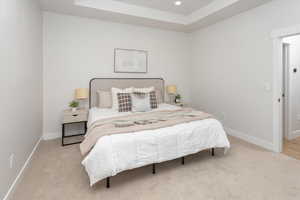 Carpeted bedroom with recessed lighting, baseboards, and a raised ceiling