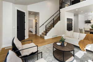 Living room with stairs, baseboards, visible vents, and light wood finished floors