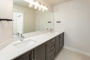 Full bath with a sink, baseboards, tile patterned floors, and double vanity