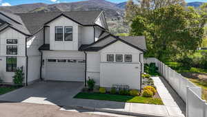 View of front facade featuring fence, a shingled roof, a garage, a mountain view, and concrete driveway