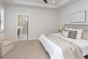 Carpeted bedroom with recessed lighting, baseboards, a tray ceiling, and ensuite bathroom
