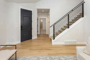 Foyer featuring stairway, baseboards, light wood-style flooring, and visible vents