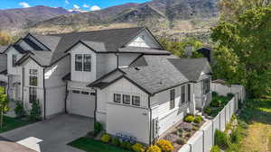 Traditional home featuring roof with shingles, fence, an attached garage, a mountain view, and driveway