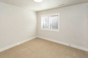 Spare room with visible vents, baseboards, and light carpet