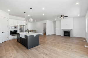 Kitchen with a ceiling fan, appliances with stainless steel finishes, a center island with sink, a sink, and recessed lighting