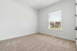 Carpeted spare room featuring baseboards, a healthy amount of sunlight, and visible vents