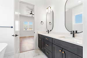 Bathroom featuring baseboards, a sink, ceiling fan, and double vanity