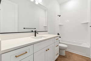 Bathroom featuring vanity, washtub / shower combination, wood finished floors, and toilet