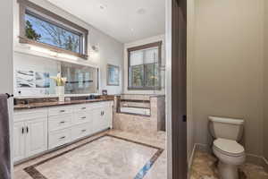 Bathroom featuring double vanity, toilet, recessed lighting, a bath, and a sink