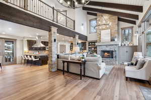 Living room featuring beam ceiling, high vaulted ceiling, a chandelier, light wood-style floors, and ornate columns