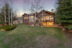 Back of property at dusk with a lawn, a chimney, and a wooden deck