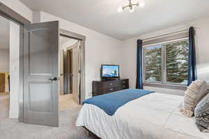Bedroom with light colored carpet and an inviting chandelier