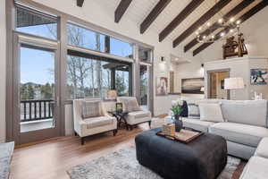 Living area with an inviting chandelier, beam ceiling, high vaulted ceiling, wooden ceiling, and wood finished floors