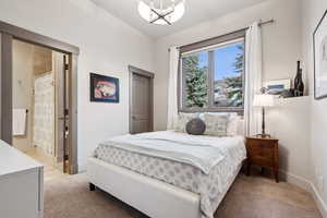 Bedroom featuring baseboards, an inviting chandelier, and light carpet