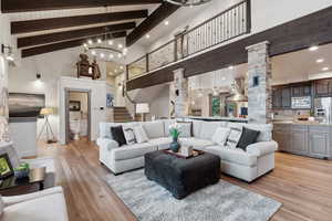 Living room featuring decorative columns, light wood finished floors, high vaulted ceiling, and beamed ceiling