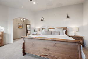 Bedroom featuring light colored carpet, arched walkways, and baseboards
