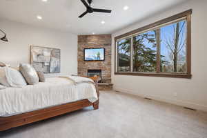 Carpeted bedroom featuring visible vents, baseboards, a stone fireplace, recessed lighting, and a ceiling fan