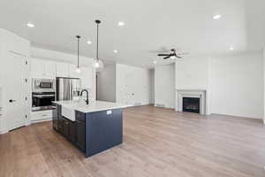 Kitchen with a ceiling fan, a sink, light countertops, stainless steel appliances, and recessed lighting
