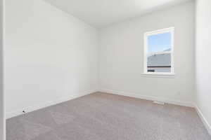 Spare room featuring baseboards, visible vents, and light carpet