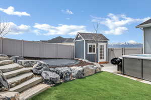 View of yard with a fenced backyard, an outdoor structure, and a trampoline