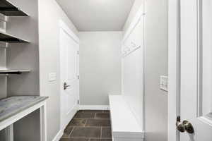 Mudroom with dark tile patterned floors, a textured ceiling, and baseboards