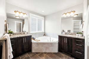 Bathroom featuring tile patterned floors, two vanities, a sink, and a garden tub